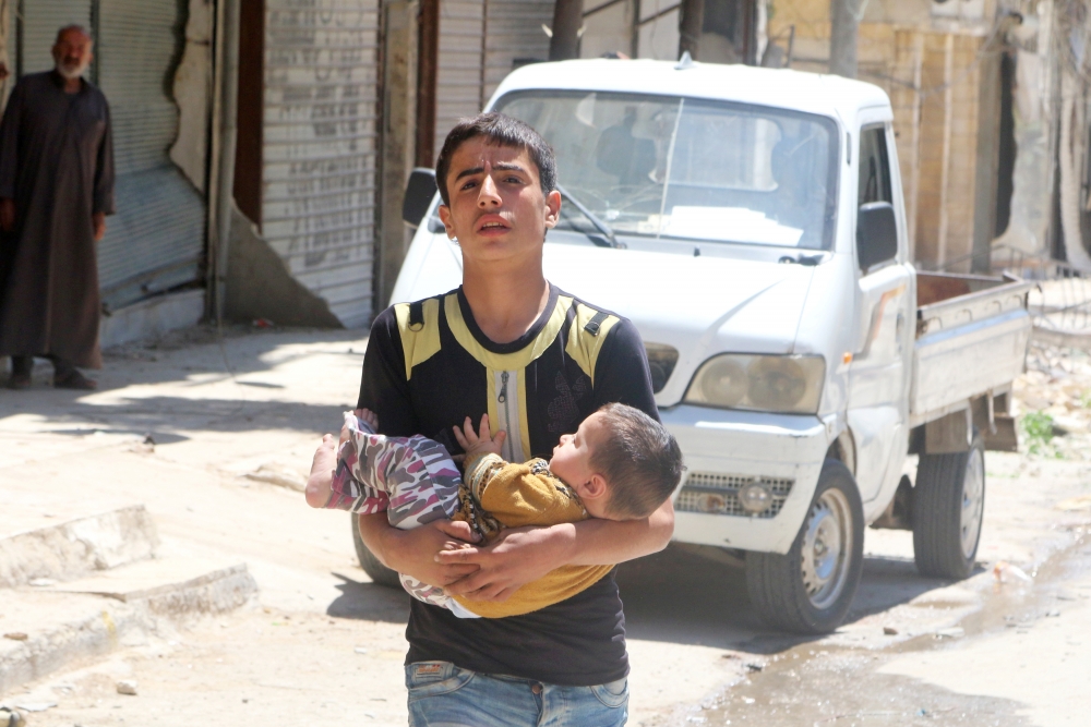 Một chàng trai bé em nhỏ chạy trốn khỏi cuộc oanh tạc tại quận al-Fardous, Aleppo vào ngày 29/4 vừa qua.